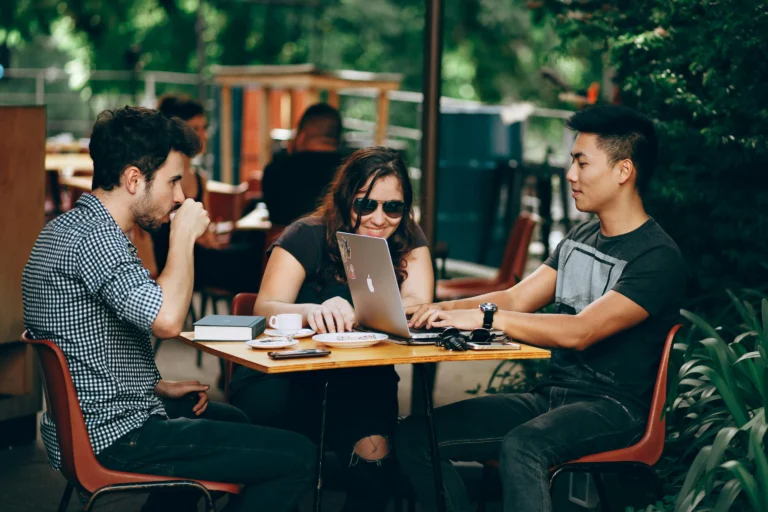 Remote workers collaborating at an outdoor café with laptops and coffee in 2026