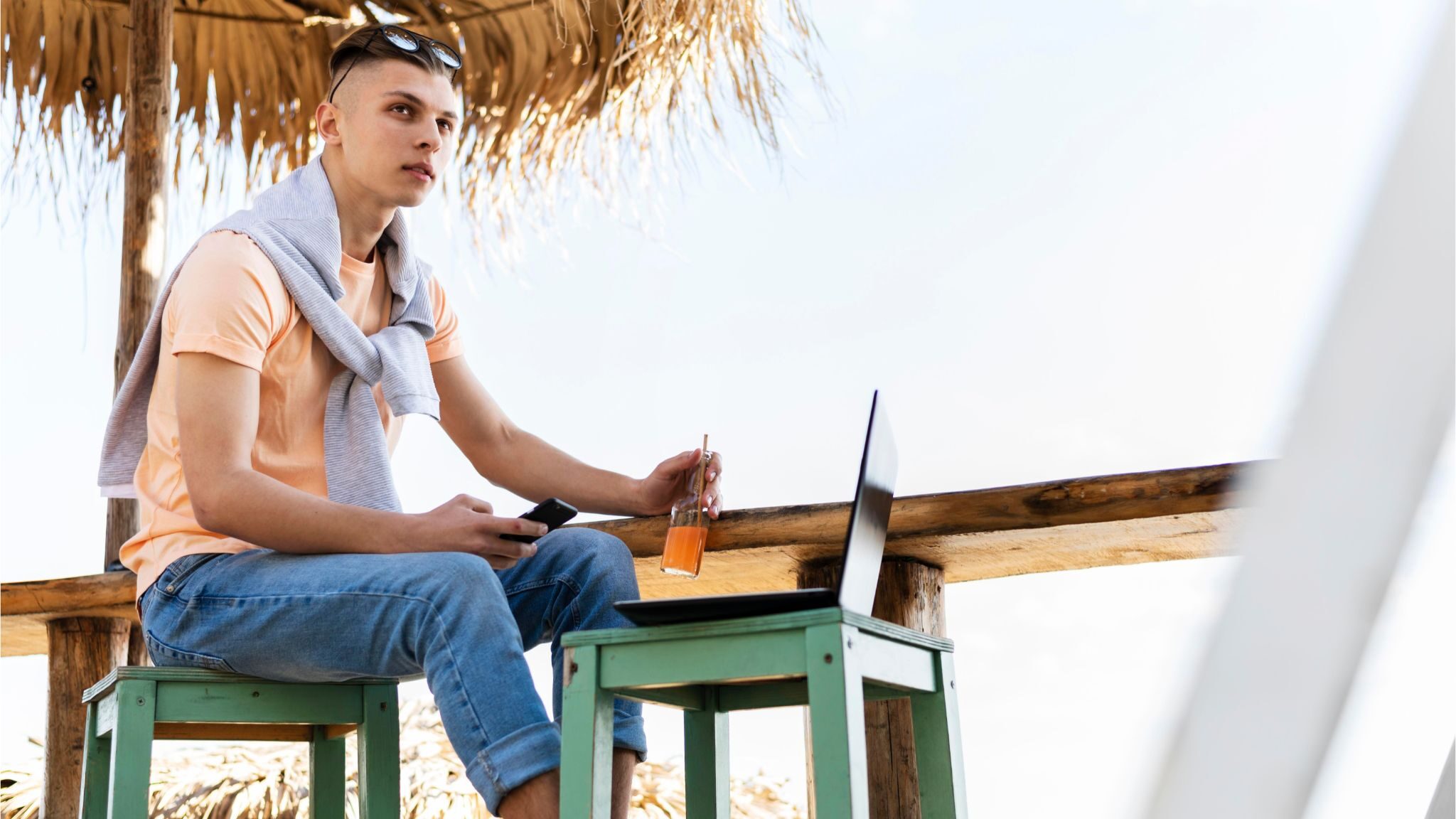 Digital nomad working remotely on laptop at tropical beach location with casual setup